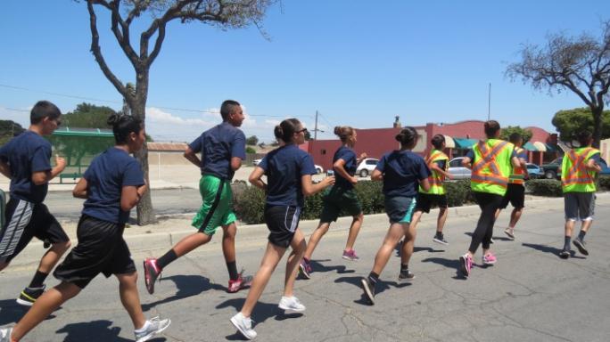 Several young adults running outside.